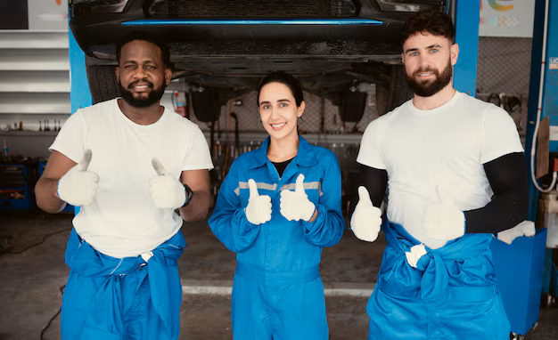 a team of mechanics posing infront of a car